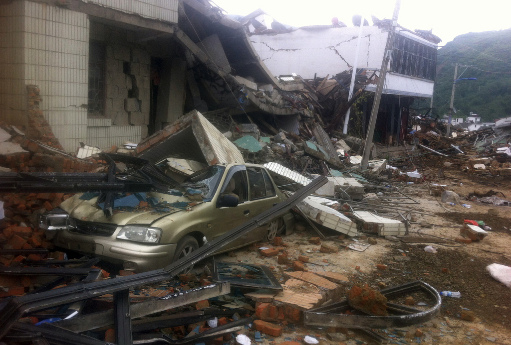 A car is crushed by a collapsed building in the epicenter of an earthquake that struck the town of Longtoushan in Ludian county in southwest China's Yunnan province Monday, Aug. 4, 2014. Rescuers dug through shattered homes Monday looking for survivors of a strong earthquake in southern China's Yunnan province that toppled thousands of homes on Sunday, killing hundreds and injuring more than a thousand people (AP Photo) CHINA OUT