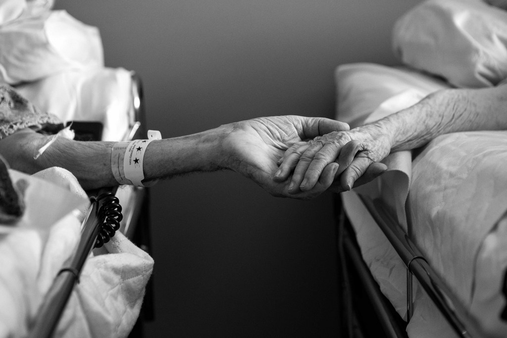 In this July, 2014 photo provided by their granddaughter Melissa Stone, Don Simpson, 90, and his wife Maxine, 87, hold hands from adjoining hospice beds in Sloan's home in Bakersfield, Calif. The couple, married 62 years, died four hours apart July 21, 2014, while lying next to each other, their family said. (AP Photo/Melissa Sloan