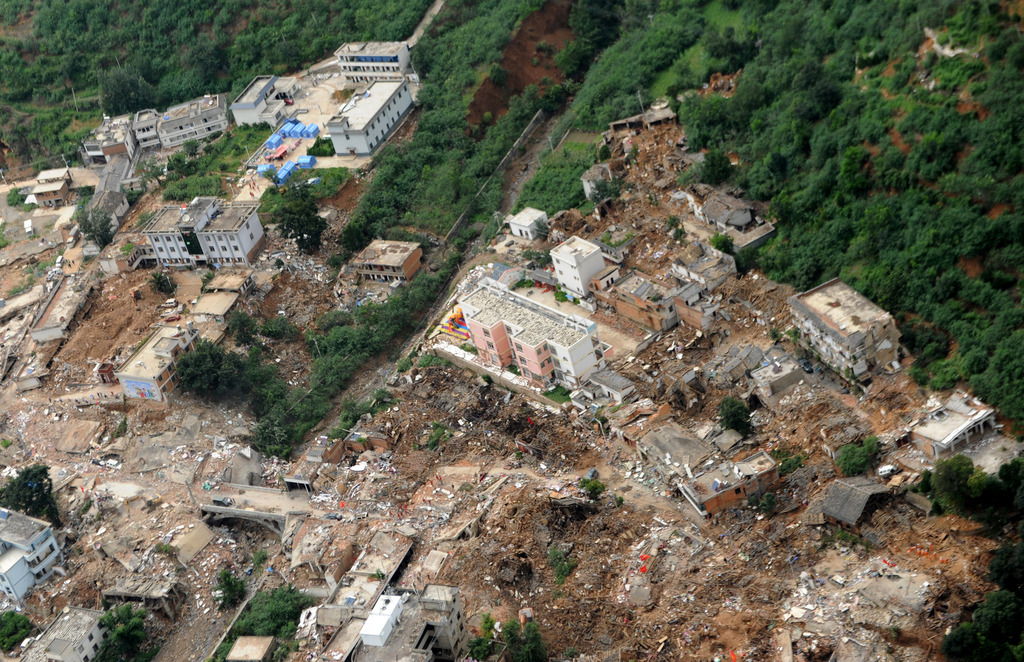 This aerial photo provided by China's Xinhua News Agency shows the quake-hit Longtoushan town, Ludian county of Zhaotong, southwest China's Yunnan Province, after Sunday's earthquake Tuesday, Aug. 5, 2014.  About 10,000 troops used pickaxes and backhoes to clear roads and dig residents from collapsed homes Tuesday after an earthquake in southwest China that killed hundreds of people. Groups of volunteers, meanwhile, used their bare hands.  (AP Photo/Xinhua, Tao Liang) NO SALES