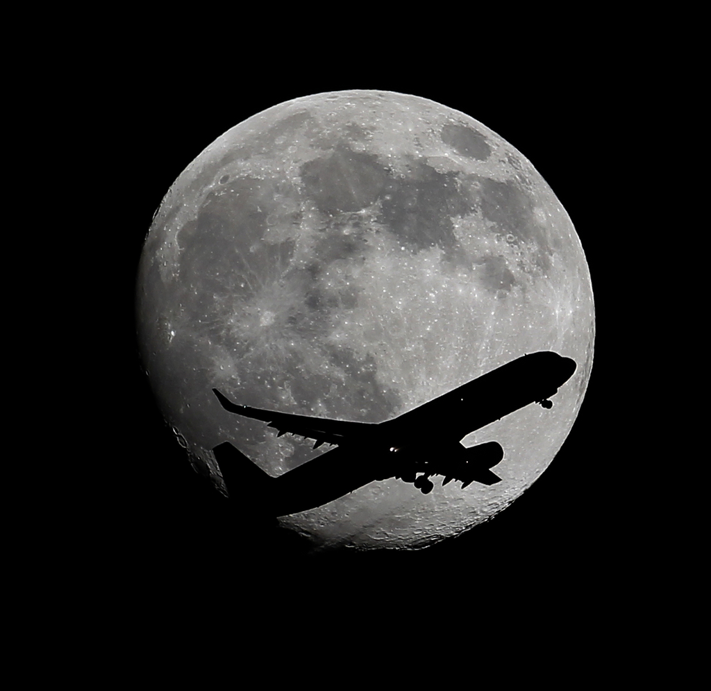 An LAX bound passenger airplane drops the wheels as it crosses the moon two days before the Full Moon and Super Moon passing over Whittier, CA., on its final approach to the Los Angeles Airport, on Friday,  Aug. 8, 2014.  (AP Photo/Nick Ut )