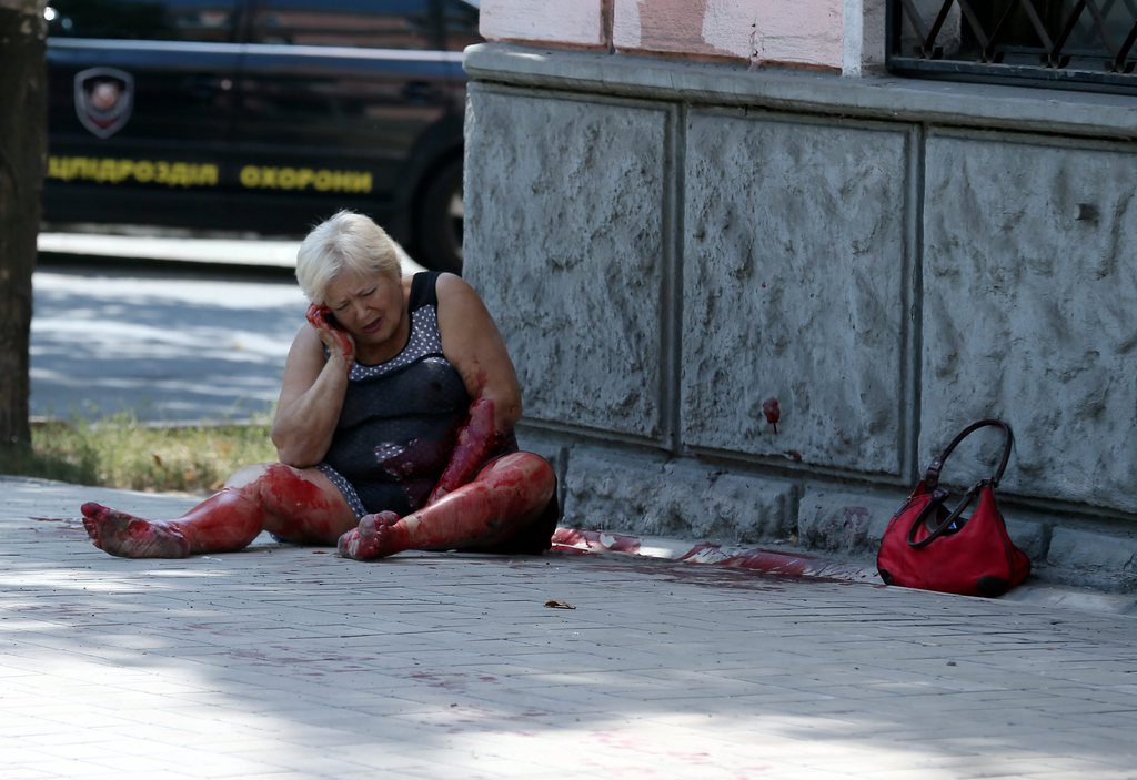 epa04353073 A wounded woman sits on the street after a mortar attack by the Ukrainian army of the center of Donetsk, Ukraine, 14 August 2014. Reports state that ten local people where wounded and one killed after the mortar attack.  EPA/SERGEI ILNITSKY ATTENTION EDITORS: PICTURE CONTAINS GRAPHIC CONTENT