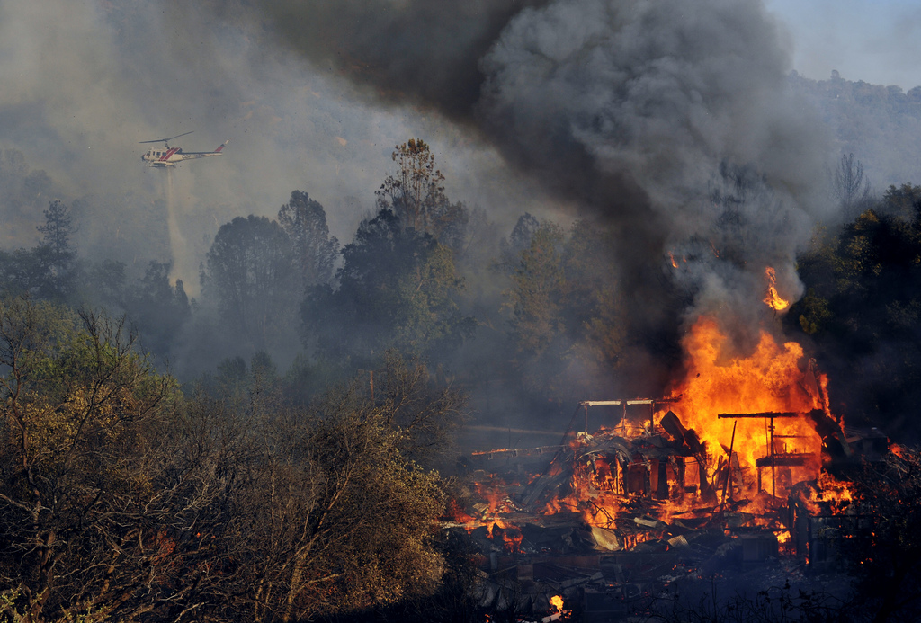 A structure burns along Highway 41 in Oakhurst, Calif., Monday, Aug. 18, 2014. One of several wildfires burning across California prompted the evacuation of hundreds of people in a central California foothill community near Yosemite National Park, authorities said. (AP Photo/The Fresno Bee, Eric Paul Zamora)