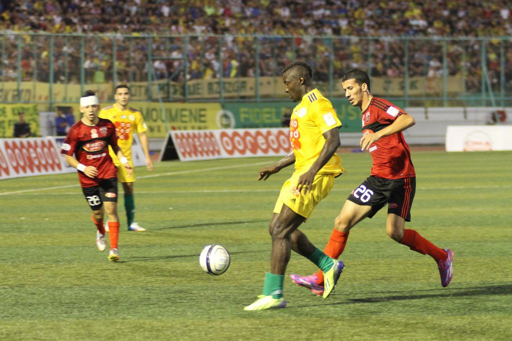 epa04366071 A photograph made available on 24 August 2014 shows Cameroonian striker Albert Ebosse Boojongo (2-R) of Algerian JS Kabylie vies for the ball with Ibrahim Boudebouda (R) of USM Alger during the Algerian championship match in Tizi Ouzou, Algeria, 23 August 2014. Ebosse, 24, died on 23 August after being hit by an object thrown from the stands at the end of the match.The JS Kabylie striker, who had scored in a 2-1 home defeat by USM Alger, was hit when fans started throwing objects from the stands as the teams returned to their changing rooms after the game.  EPA/STR