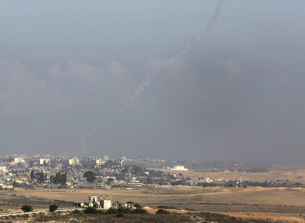 epa04345279 A rocket fired by militants inside the northern Gaza Strip rises with a trail of smoke as it launches from a distance behind the recently demolished buildings (foreground) towards southern Israel, on 08 August 2014, as the 72-hour ceasefire expires. The Israeli military reports about one dozen rockets have been fired towards Israel since the ceasefire expired. Hamas said it was continuing its indirect talks with Israel, after the expiry of a three-day ceasefire on early 08 August. There was no agreement on another truce, spokesman Sami Abu Zuhri said, 'but the negotiations are continuing'.  EPA/JIM HOLLANDER
