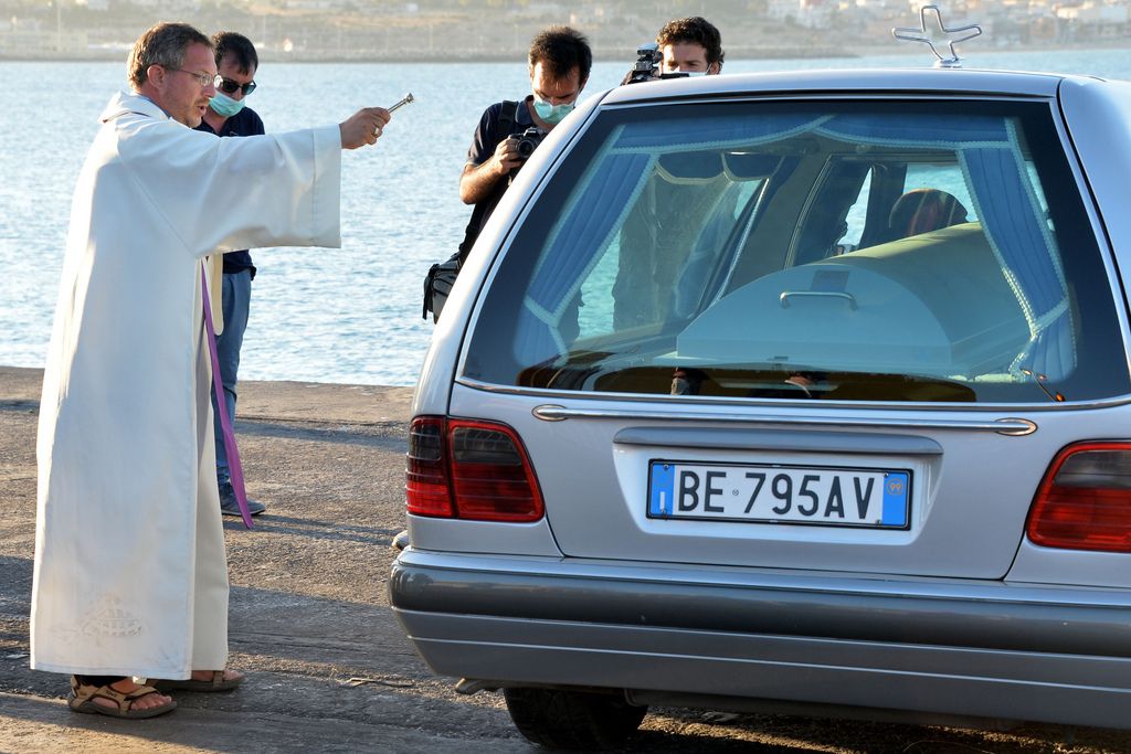 A priests blesses a coffin containing the body of one of some 30 would-be migrants heading to Italy, the latest deaths in a surge of immigration to Europe, after it was towed to the port of  of Pozzallo, on the southern tip of Sicily, Italy, Tuesday, July 1, 2014. The boat was carrying nearly 600 people and the remaining 566 survivors were rescued by the navy frigate Grecale and were headed to Pozzallo as well. The estimated 30 corpses were discovered in the bow of the boat during the rescue, according to a navy statement. The victims were believed to have suffocated or drowned. (AP Photo/Carmelo Imbesi)