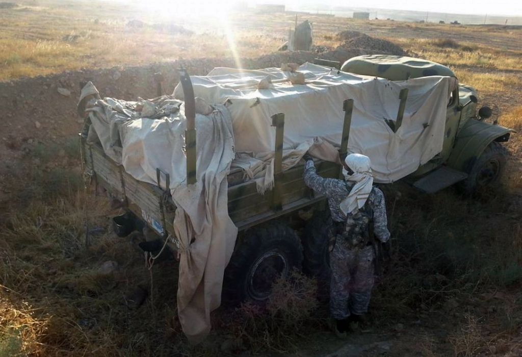 This image posted by the Raqqa Media Center shows a fighter from the Islamic State group inspecting a military truck in Raqqa, Syria, Thursday, Aug. 7, 2014. The Islamic State militants seized the Brigade 93 base overnight after days of heavy fighting, according to the Syrian Observatory for Human Rights and the Raqqa Media Center, an activist collective. The base lies some 40 miles (60 kilometers) from the provincial capital of Raqqa, a stronghold for the Islamic State group. (AP Photo/Raqqa Media Center)