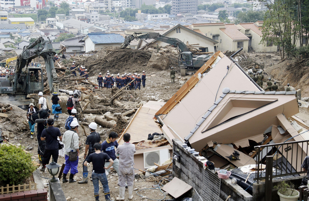 People watch rescuers make search operation in a mud-covered residential area following a massive landslide in Hiroshima, western Japan, Sunday, Aug. 24, 2014.  About 2,800 police and military personnel have been searching for the victims, at times suspending their work to reduce risks from further slides. Rescue workers said the massive amounts of mud slowed them down, while narrow alleyways in the area made it difficult to use heavy machinery to remove debris. (AP Photo/Kyodo News) JAPAN OUT
