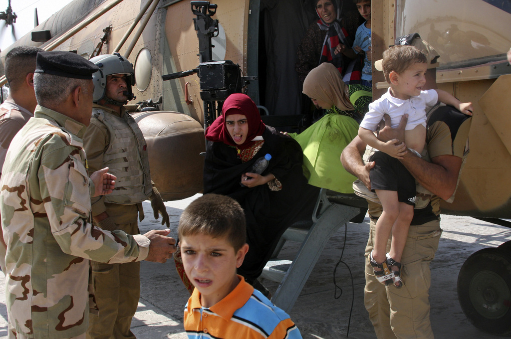 Iraqi Shiite Turkmens disembark from an Iraqi Army helicopter aid flight that brought supplies to Amirli, a town that has been completely surrounded by militants with the Islamic State group since mid-July, after being evacuated from Amirli, in al-Muthana airport, Baghdad, Iraq, Saturday, Aug. 30, 2014. The Iraqi military has been flying in food, medicine and weapons, but residents say the aid isn't enough, and that many are falling victim to disease and heat stroke in the relentless August heat. (AP Photo)