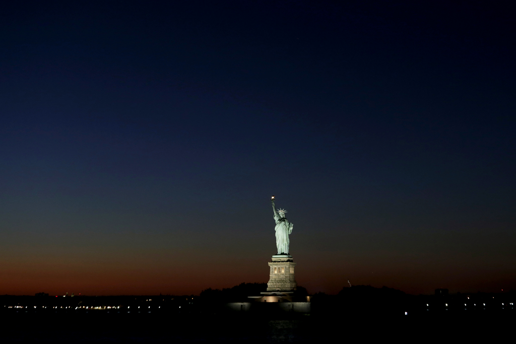 Light from the setting sun gives a backdrop to the Statue of Liberty, Tuesday, Sept. 23, 2014, in New York. (AP Photo/Julio Cortez)