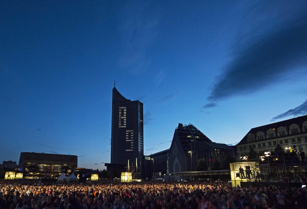 Thousands of people stand in front of a tower building illuminated with '89' during the commemoration at the 25th anniversary of the peaceful revolution in Leipzig, Germany,  Thursday, Oct. 9, 2014. The city commemorates the autumn of 1989 when the so-called Monday demonstrations ushered in the Fall of the Berlin Wall. (AP Photo/Jens Meyer)