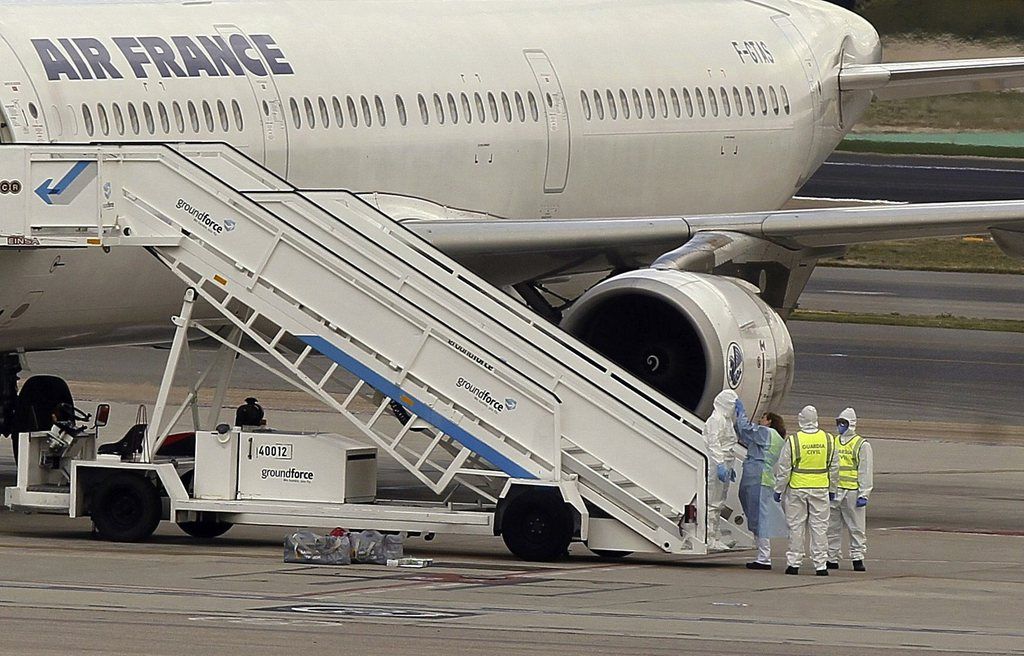 epa04449161 Medical staff wearing protection suits stand next to the Air France Airbus A321 which landed at Barajas International Airport in Madrid, Spain, 16 october 2014. Spanish authorities have isolated an Air France plane at Madrid airport over concerns that a passenger who was shivering and had a fever may be infected with Ebola, airport officials said. The plane, which was travelling from Paris, was ordered to taxi to a remote area of the airport and the passenger was transported to an isolation unit at Madrid's Carlos III hospital, the efe news agency reported. The passenger is expected to be transferred at carlos III hospital.  EPA/PACO CAMPOS