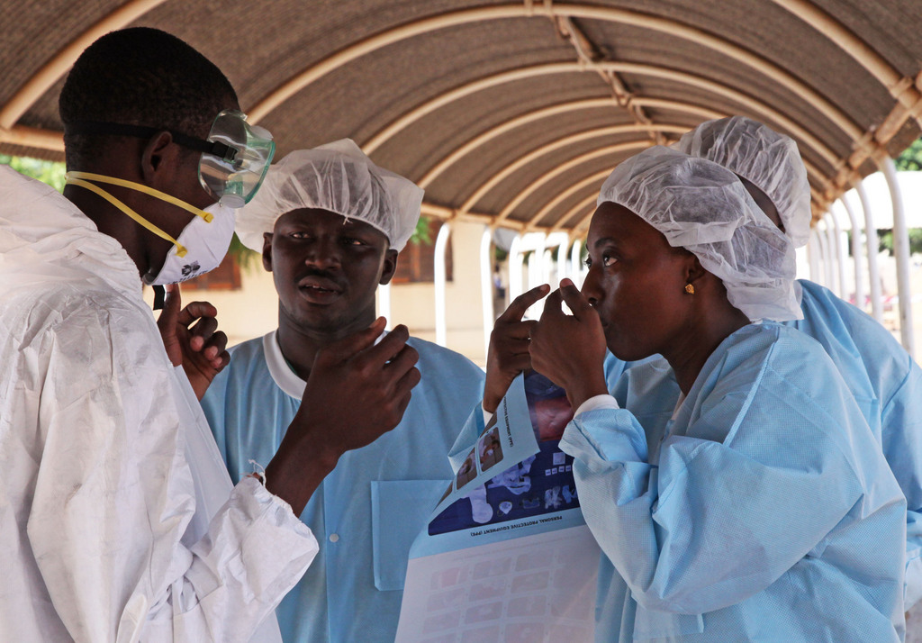 In this photo taken Saturday, Oct. 25, 2014, a  health worker, right, briefs another, left, on the use of their Ebola security gear before working with diseased Fanta Kone at a Ebola virus center in  Kayes, Mali. After 2-year-old Fanta Kone?s father died in southern Guinea, the toddler?s grandmother took her from the forested hills where the Ebola outbreak first began months ago to bring her home to Mali. It wasn?t long, though, before the little girl started getting nosebleeds.  (AP Photo/Baba Ahmed)