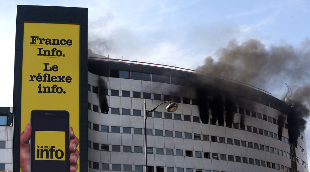 Black smoke are pouring from windows of the state radio headquarters, known as Maison de la Radio, in Paris, France, Friday, Oct.31, 2014. The massive building was undergoing renovations when the fire began. Board reads: France Info station, the news instinct. (AP Photo/Thibault Camus)