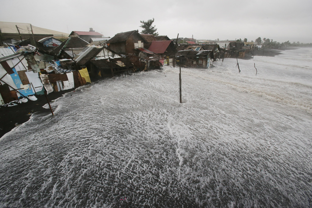 Strong waves crash into coastal houses as Typhoon Hagupit pounds Legazpi, Albay province, eastern Philippines on Sunday, Dec. 7, 2014.  Typhoon Hagupit knocked out power in entire coastal provinces, mowed down trees and sent more than 650,000 people into shelters before it weakened Sunday, sparing the central Philippines a repetition of unprecedented devastation by last year's storm.(AP Photo/Aaron Favila)