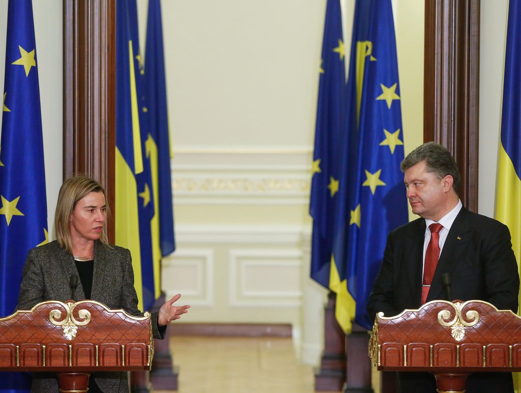 epa04531578 Ukrainian President Petro Poroshenko (R) listens to Federica Mogherini (L), the High Representative of the EU for Foreign Affairs and Security Policy, as they face the media to make a statement following their meeting in Kiev, Ukraine, 16 December 2014. Mogherini is visiting Kiev for a series of meetings with the Ukrainian President and Prime Minister, the leaders of political groups in the parliament and representatives of Ukrainian civil society.  EPA/ROMAN PILIPEY