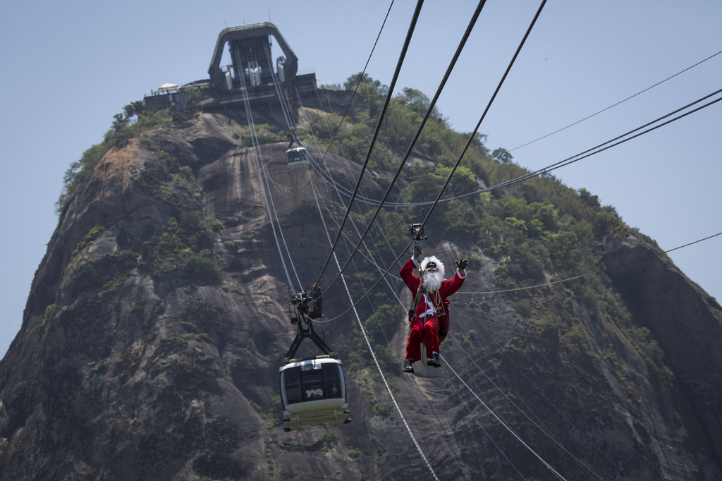 A man dressed as Santa Claus descends the Sugar Loaf mountain on a zip line after riding atop the cable car in Rio de Janeiro, Brazil, Thursday, Dec. 18, 2014. (AP Photo/Felipe Dana)