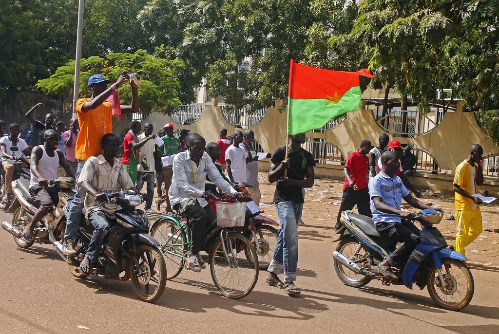 epa04471578 Men from Burkina Faso cheer and wave flags in the capital Ouagadougou following the resignation of the president of Burkina Faso in Ouagadougou, Burkina Faso, 31 October 2014. Burkina Faso army chief Honore Traore announced Friday he had taken power after president Blaise Compaore gave in to pressure from tens of thousands of demonstrators and resigned.  EPA/STR