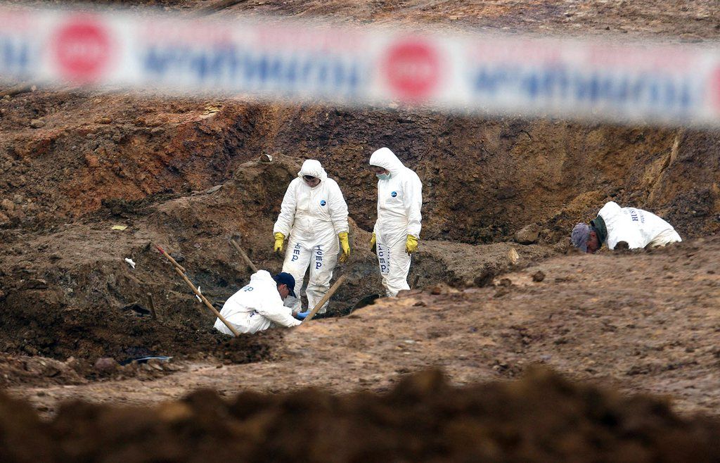 epa03900900 Forensic experts examine a mass grave containing the remains of Bosnian Muslim and Croats in the village of Tomasica, near the Bosnian town of Prijedor, 260km north west of Sarajevo, on 07 October 2013. Reports state that 94  bodies of Bosnian Muslims and Croat killed were buried in a mass grave by Serb forces at the beginning of Bosnia's 1992-95 war.  EPA/STR