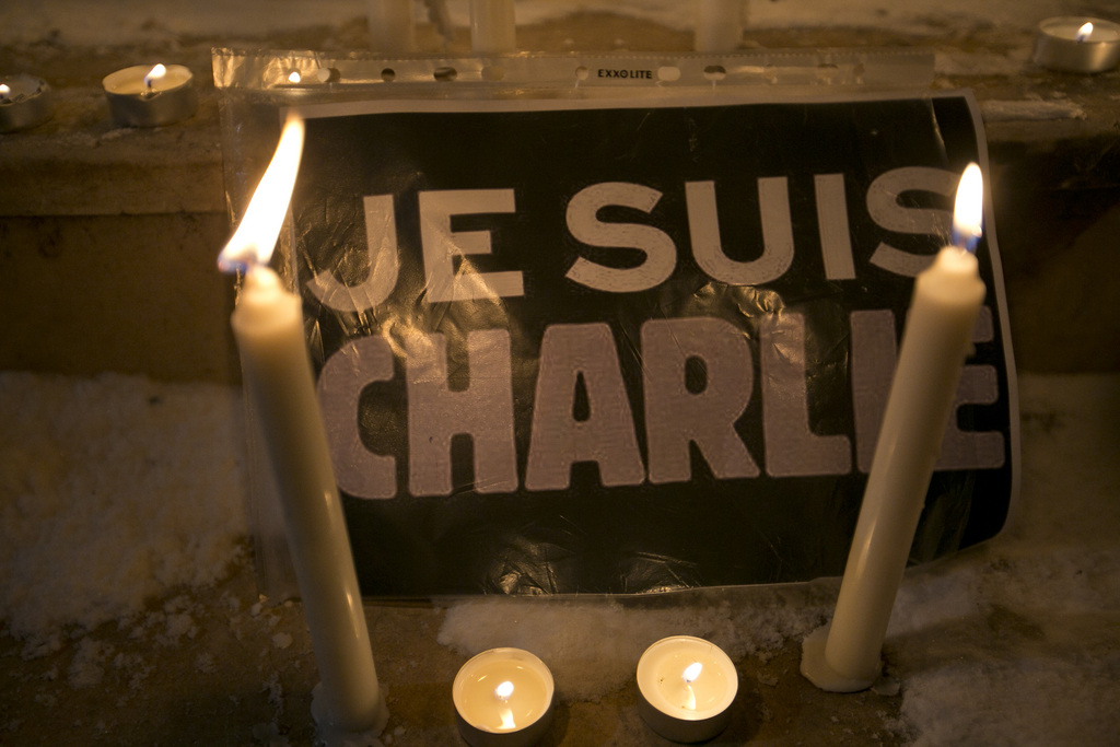 Candles are lit near a sign that read in French "I am Charlie" lights a candle during a demonstration in solidarity with those killed in an attack at the Paris offices of the weekly newspaper Charlie Hebdo  in Kosovo capital Pristina, Wednesday, Jan. 7, 2015. Masked gunmen stormed the the satirical newspaper methodically killing at least 12 people Wednesday, including the editor, before escaping in a car. It was France's deadliest postwar terrorist attack. (AP Photo/Visar Kryeziu)