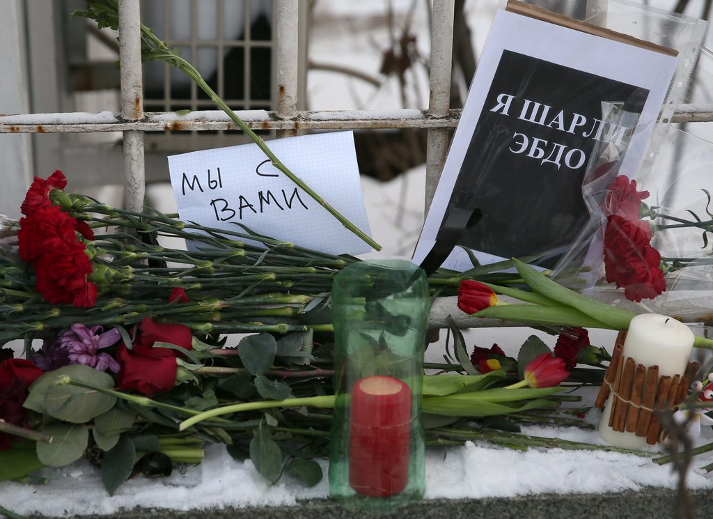 epa04550577 Flowers and signs in Russian reading 'We are with you' and 'I'm Charlie Hebdo', are left in solidarity with those killed in the shooting of 12 people at the satirical magazine Charlie Hebdo, in front of the French embassy in Moscow, Russia, 08 January 2015. At least 12 people were killed 07 January 2015 in a terrorist attack against satirical French magazine 'Charlie Hebdo' in Paris.  EPA/SERGEI ILNITSKY