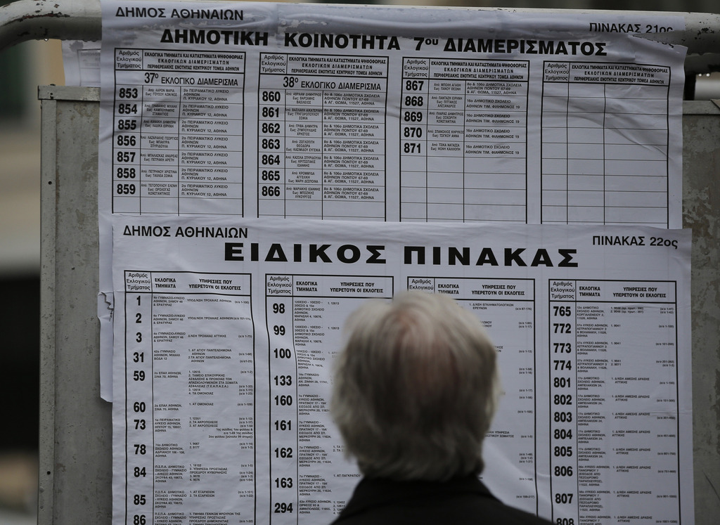 A man checks boards with lists of voting stations in central Athens, Saturday, Jan. 24, 2015. The radical left main opposition Syriza party, which has vowed to rewrite the terms of Greece's international bailout, is expected to defeat Prime Minister Antonis Samaras' conservatives as Greece goes to the polls Sunday, Jan. 25, 2015 in a snap general election. Although expected to win, it is unclear whether Syriza will get enough parliamentary seats to form a government alone, or will have to seek a coalition deal with other parties. (AP Photo/Lefteris Pitarakis)