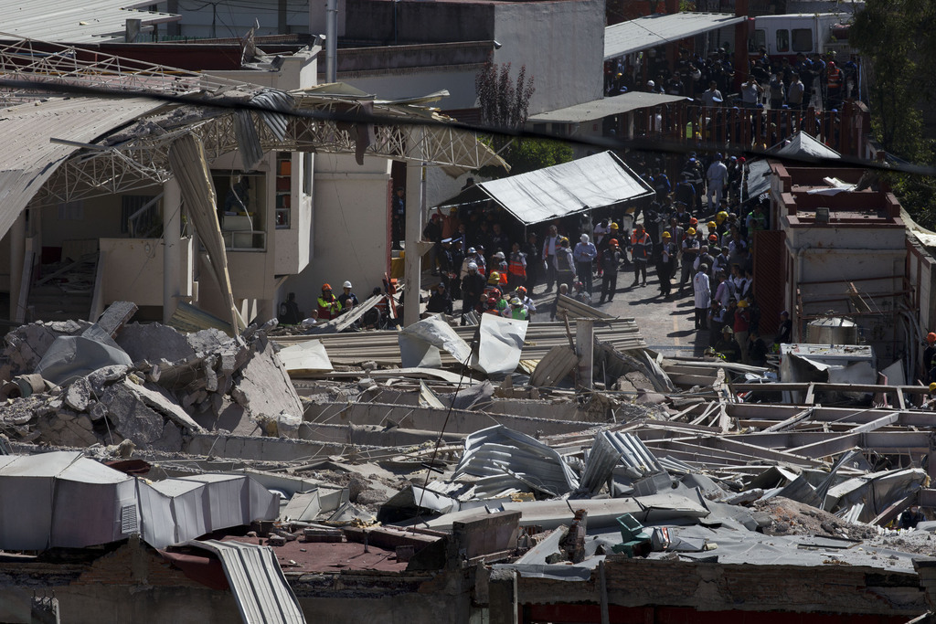 Rescue workers and police stand around the wreckage of a maternity and children's hospital after a gas truck exploded in Cuajimalpa on the outskirts of Mexico City, Thursday, Jan. 29, 2015. The explosion, which collapsed the majority of the building, occurred in the morning when a tanker truck was making a routine delivery of gas to the hospital kitchen and gas started to leak. (AP Photo/Rebecca Blackwell)
