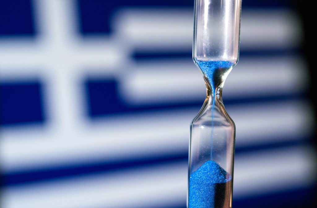 epa04624989 A picture taken 17 February 2015 in Germany shows an hourglass in front of a Greek national flag, illustrating that time is running short for an agreement on a new bailout deal for Greece. The newly elected Greek government is seeking to renegotiate the country's bailout and austerity conditions with the EU.  EPA/PATRICK PLEUL