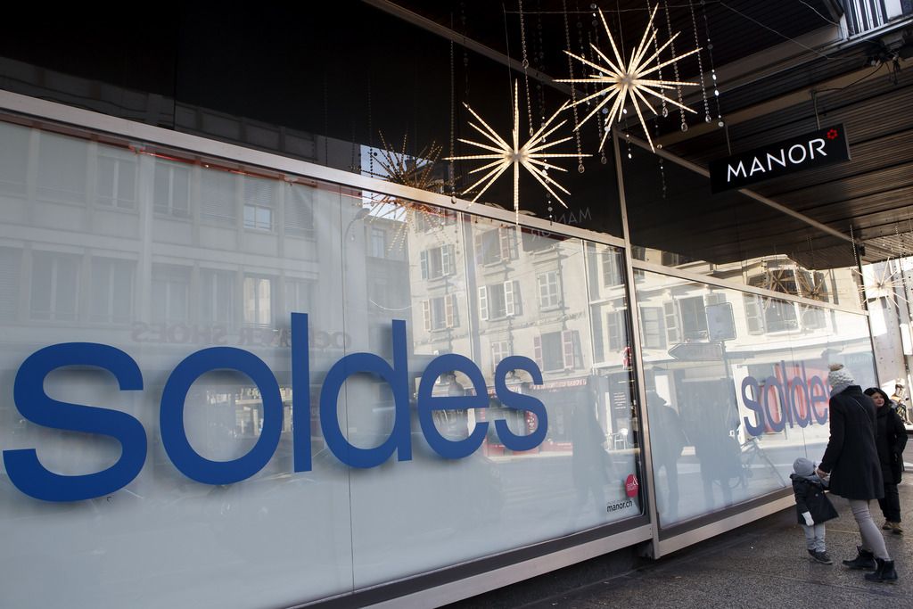 Des personnes passent devant une vitrines du grand magasin Manor lors du premier jour des Soldes, ce vendredi 26 decembre 2014 a Geneve. (KEYSTONE/Salvatore Di Nolfi)