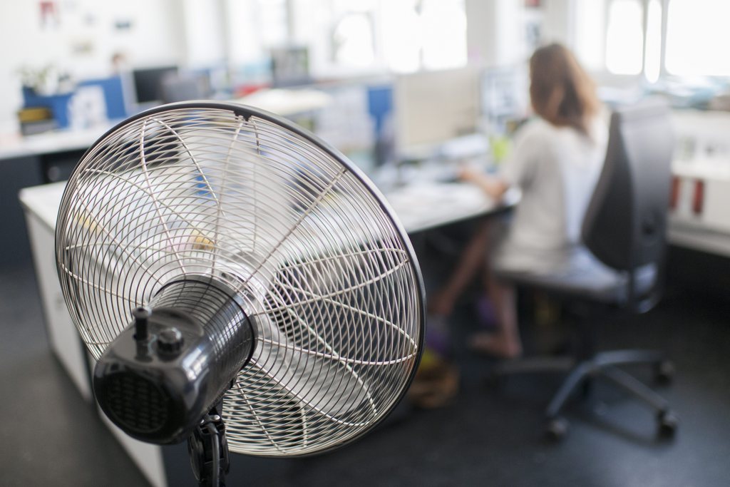 Eine Frau kuehlt sich mit einem Ventilator im Buero ab, aufgenommen am Freitag, 26. Juli 2013 in Zuerich. (KEYSTONE/Ennio Leanza)