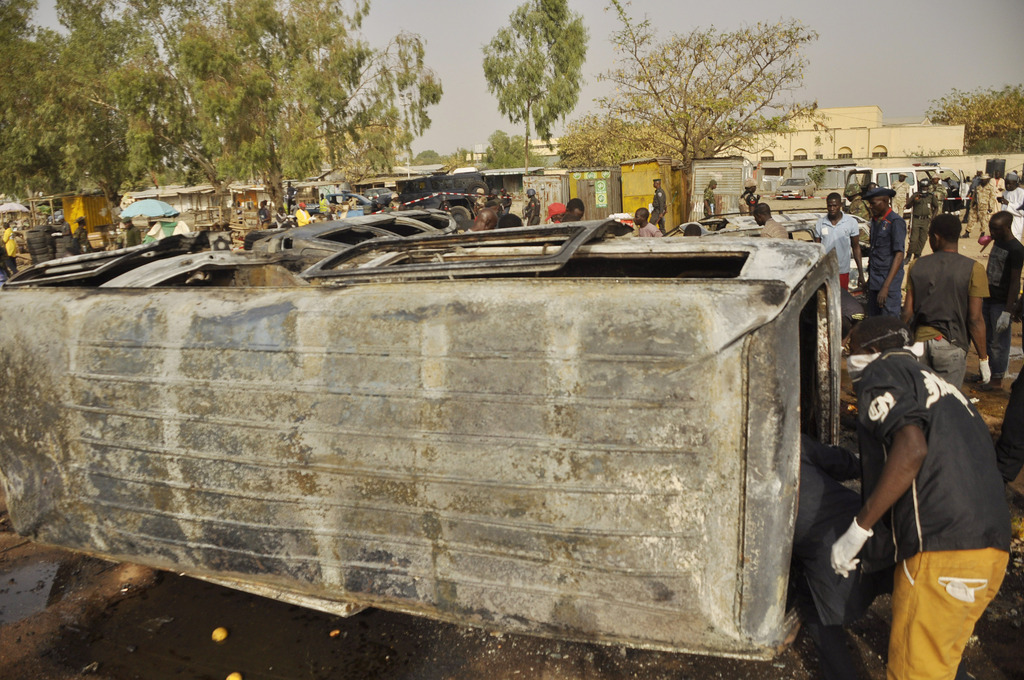 Men inspect a bus  following a suicide bomb explosion  in a bus station in Kano, Nigeria. Tuesday, Feb. 24, 2015. Teenage suicide bombers, suspected to be Boko Haram extremists, killed at least 24 people in separate blasts Tuesday at crowded bus stations in two northern Nigerian cities 300 kilometers (200 miles) apart. (AP Photo/Sani Maikatanga )