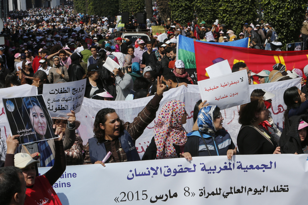 An activist, left, holds portrait of Wafae Charaf as protesters from the Moroccan Association of Human Rights shout slogans during a march through the streets of the Moroccan capital marking International Women's Day in Rabat, Morocco, Sunday, March 8, 2015. The group are asking the freedom of Activist Wafae Charaf arrested in Tangier and sentenced to two years in prison. (AP Photo/Abdeljalil Bounhar)