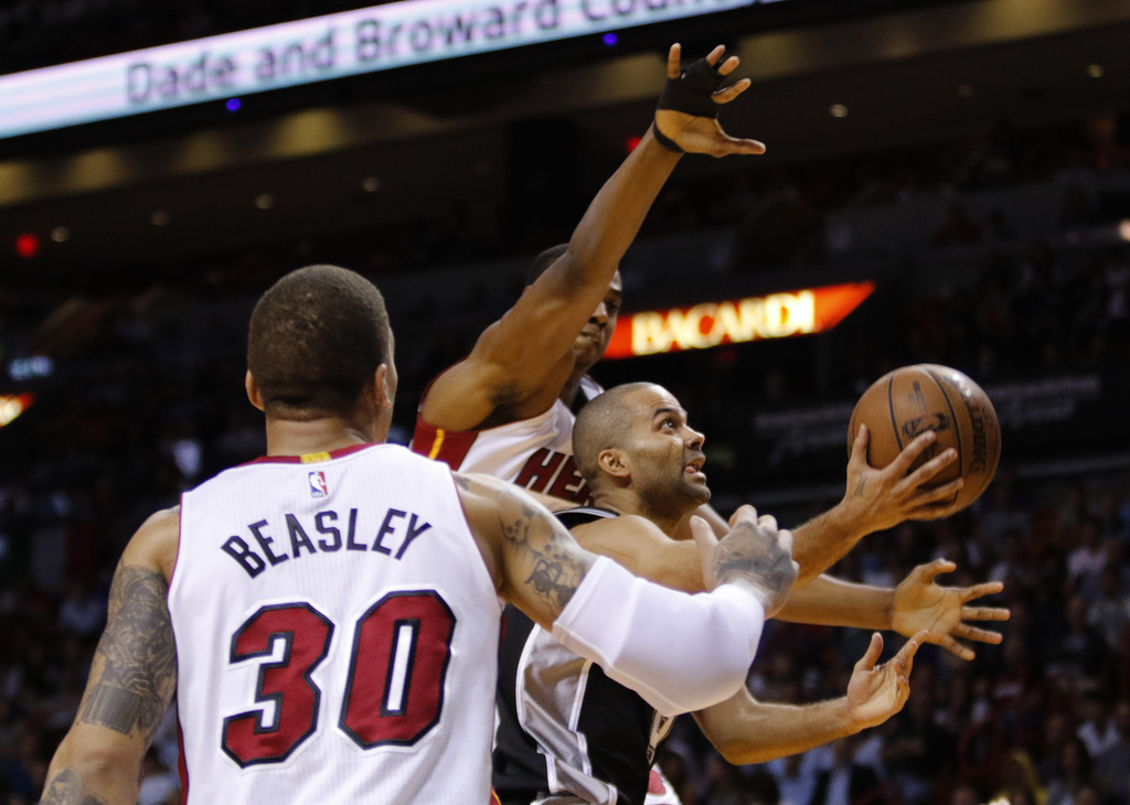 San Antonio Spurs guard Tony Parker, right, drives between Miami Heat defenders including Michael Beasley during an NBA basketball game, Tuesday, March 31, 2015, in Miami. The Spurs won the game 95-81. (AP Photo/Joe Skipper)