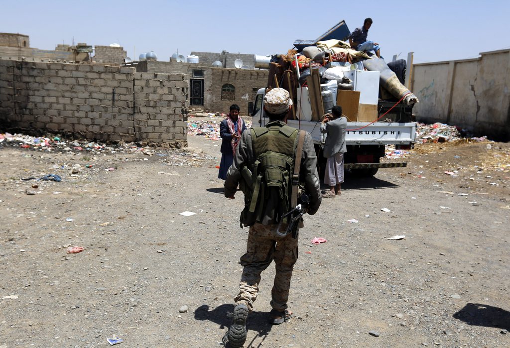 epa04688247 An armed member of Houthi militia walks towards Yemenis packing up their belongings into the back of a truck after their house was allegedly hit by an airstrike of the Saudi-led coalition targeting Houthi rebels? positions in Sana?a, Yemen, 31 March 2015. A Saudi-led military alliance mounted a series of airstrikes against Yemen's Houthi rebels and troops allied to the Houthis in Yemen on 31 March, the sixth day of an air campaign that could turn the country into a proxy battleground for Saudi Arabia and regional rival Iran. Warplanes bombed the Houthis' positions in the rebel-held capital Sana'a and the western city of Hodeida.  EPA/YAHYA ARHAB