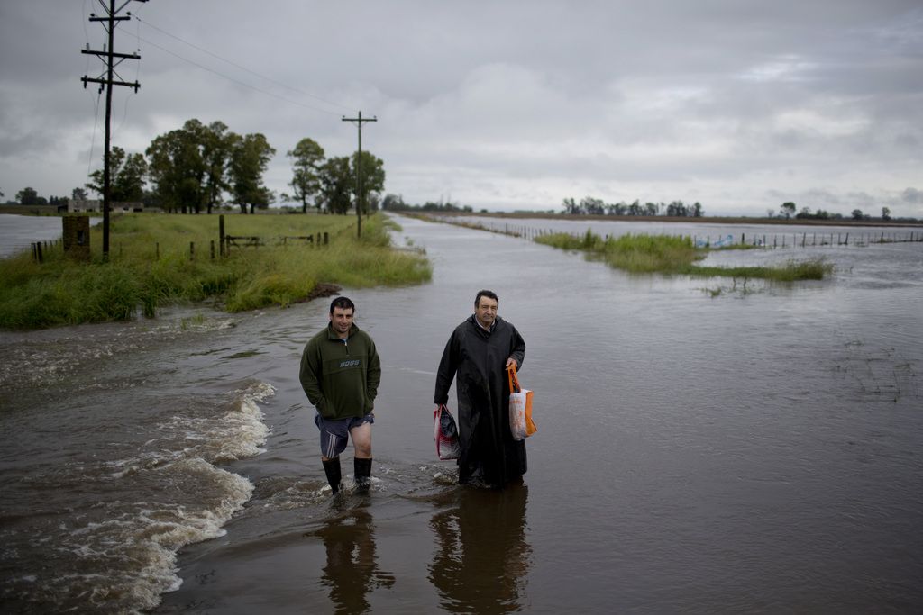 Men wade through flooded roads near Carmen de Areco, Argentina, Monday, Nov. 3, 2014. Heavy rain since Thursday has killed two people in the province of Buenos Aires and thousands have evacuated the area. (AP Photo/Natacha Pisarenko)