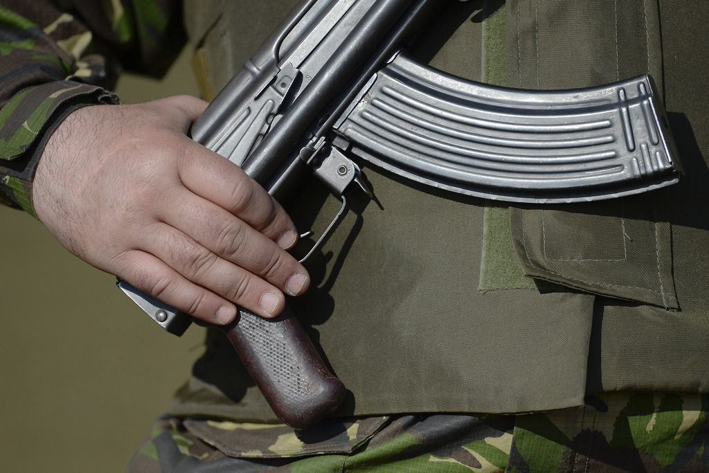 A woman reacts as she walks past pro-Russian rebels guarding the Zasyadko mine in Donetsk, Ukraine Wednesday March 4, 2015.  An explosion at the Zasyadko coal mine in war-torn eastern Ukraine killed 32 workers on Wednesday, the speaker of Ukraine's parliament said. Rebels who control the area, however, confirmed only one death. (AP Photo/Vadim Ghirda)