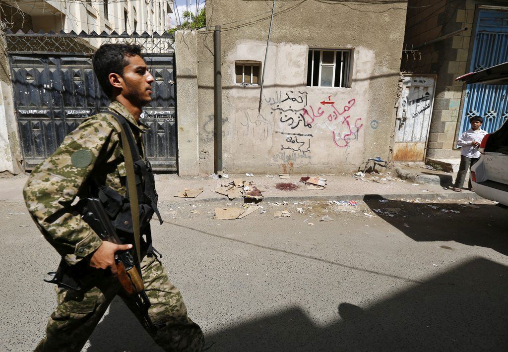 epa04667588 A member of the Houthi militia walks past the scene of a drive-by shooting in which one Houthi official was killed, Sana?a, Yemen, 18 March 2015. According to reports, a senior Houthi media official, Abdul-Karim al-Khiwani, was killed when unidentified gunmen driving a motorbike opened fire on him in Sana?a, since taking over Sana'a September 2014 the Houthis have come into conflict with rival groups, most notably al-Qaeda in the Arabian Peninsula (AQAP) who have carried out a number of deadly attacks on the Zaidi Shiite group coming from Yemen's north.  EPA/YAHYA ARHAB