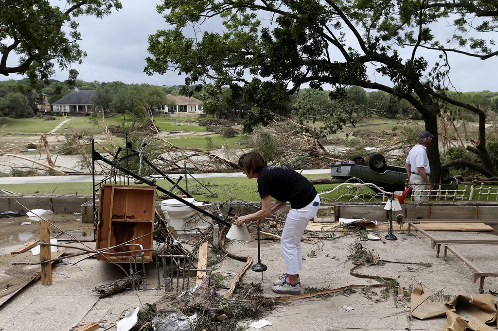epa04767853 Debi Welsh, of Corpus Christi, Texas, USA, picks up a lamp as family and friends clean up what's left after their home was washed away by a record flood in Wimberley, Texas, USA, 25 May 2015. 12 people are missing and between 1,200 to 1,300 buildings damaged or destroyed by flooding.  EPA/JERRY LARA MANDATORY CREDIT: San Antonio Express-News via european pressphoto agency  EDITORIAL USE ONLY