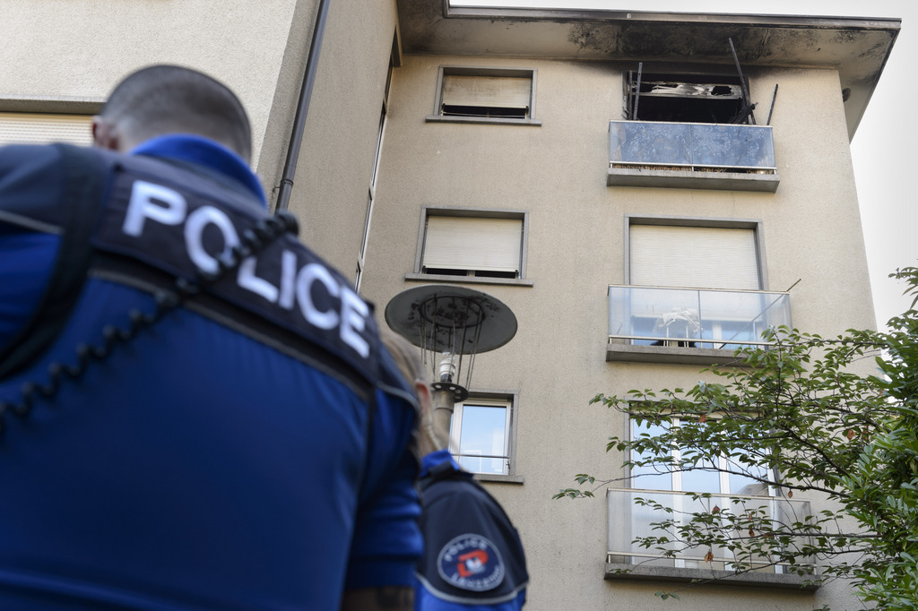 Un policier de la Police de Lausanne est photographie devant la fenetre carbonisee ou une personne est decedee suite a un incendie ce samedi 27 juin 2015 a Lausanne. (KEYSTONE/Laurent Gillieron)