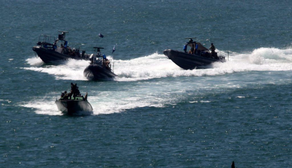 epa02188337 Four small Israeli navy vessels containing navy commandos speed into the port of Ashdod in southern Israel on 05 June 2010. Earlier the Israeli navy boarded and took cotrol of the Free Gaza flotilla ship, the Rachel Correa off the coast of the Gaza Strip with no violence, according to the Israeli army spokesman, after issuing several invitations for the ship to enter Ashdod port and have its cargo inspected before being brought into the Gaza Strip. Behind are freight ships outside the Ashdod port.  EPA/JIM HOLLANDER