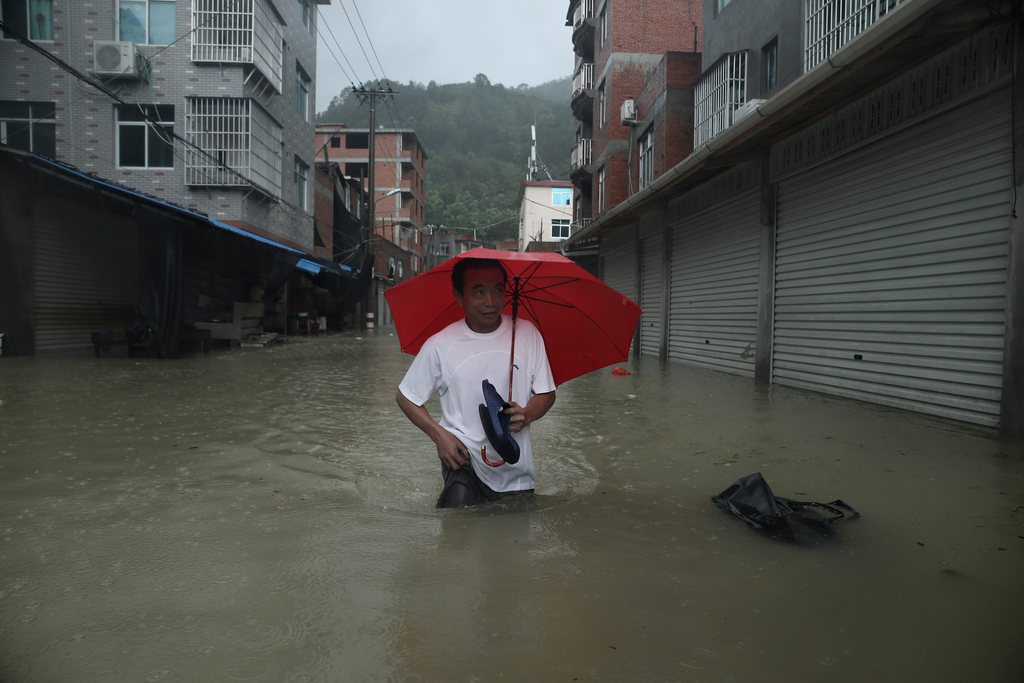 epa04877887 A man walks in the flooded Chengli village in Ningde, south-east China's Fujian province, 09 August 2015. Typhoon Soudelor landed in Fujian 08 August night, bringing torrential rains and strong gusts.  EPA/LIU TAO CHINA OUT