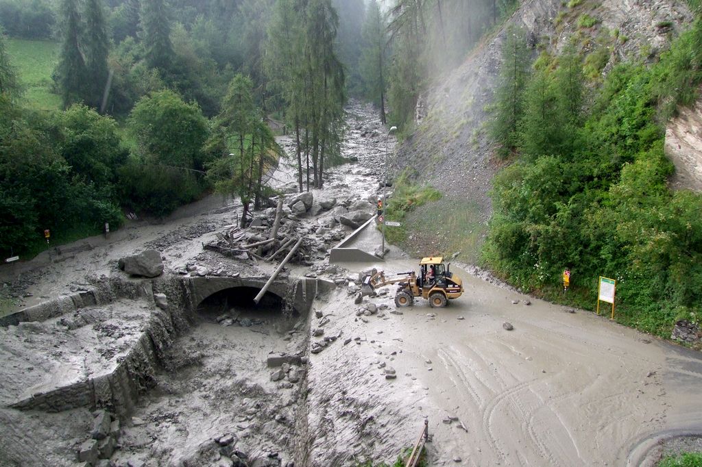 HANDOUT - Ein Bagger raeumt Geroell weg, nach einem Murgang in Scuol, am Donnerstag, 23. Juli 2015. Kraeftige Gewitterregen haben am spaeten Donnerstagnachmittag in Scuol den Clozza-Bach stark anschwellen lassen, wie die Buendner Polizei am Freitag, 24. Juli mitteilte. Ein Personenwagen sei fast bis zur Inneinmuendung heruntergespuelt worden. Personen seien keine zu Schaden gekommen. Bereits am Mittwoch kam es in der Umgebung von Scuol zu einem Murgang. (HANDOUT Kantonspolizei Graubuenden). *** NO SALES, DARF NUR MIT VOLLSTAENDIGER QUELLENANGABE VERWENDET WERDEN ***