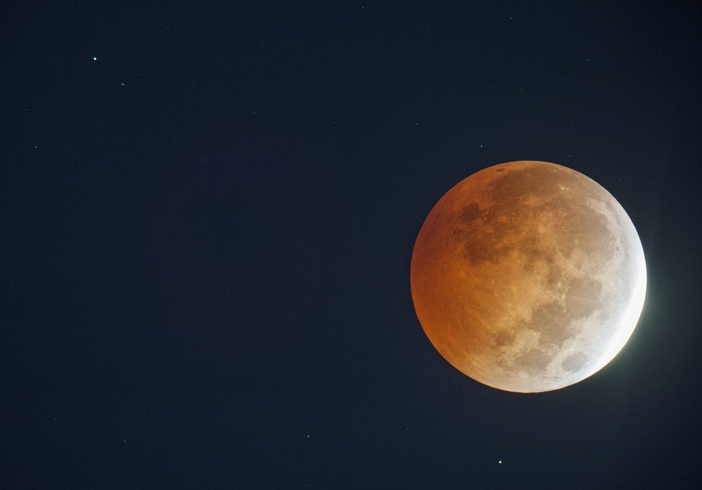 A lunar eclipse appears above Wade, N.C.  in a picture made through an amateur astronomer's 8-inch telescope on Wednesday, Oct. 8, 2014.  The moon appears orange or red, the result of sunlight scattering off Earth's atmosphere. This is known as the blood moon. (AP Photo/The Fayetteville Observer, Johnny Horne) MANDATORY CREDIT