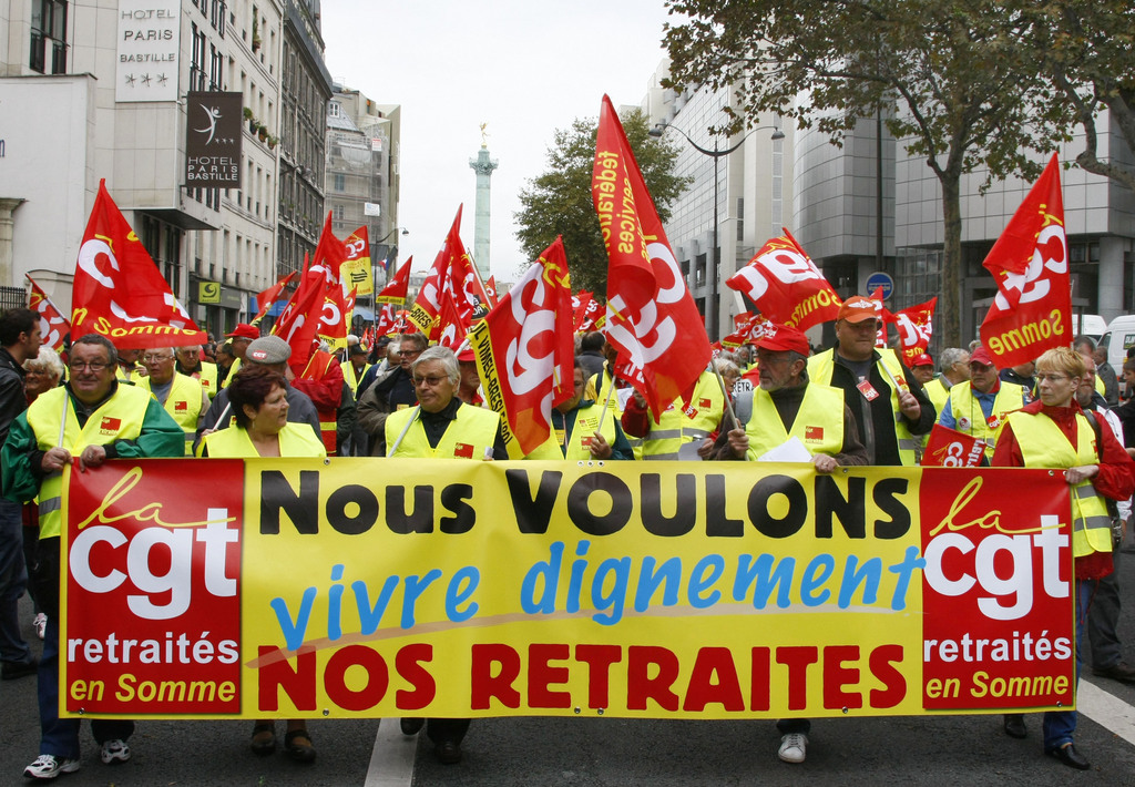 Demonstrators march with red flags during a rally to protest France's decision to raise the retirement age and retirement pensions low level, in Paris, Thursday, Oct. 6, 2011. Sign reads: "We Want to Live our Retirement in Dignity".(AP Photo/Michel Spingler)