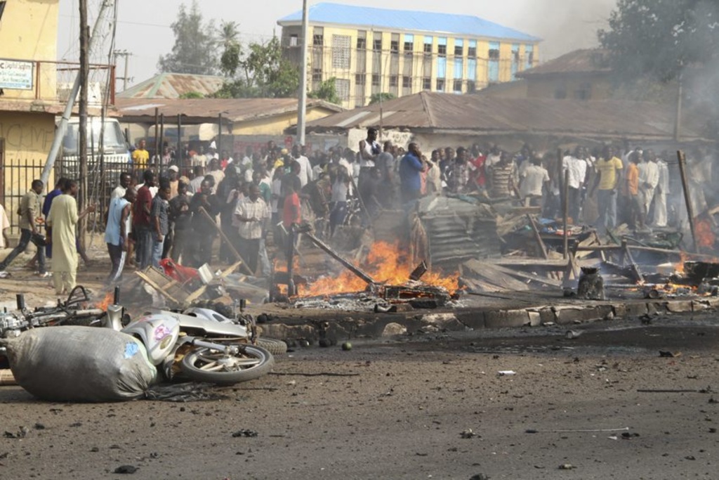 People gather at the site of a bomb explosion at a road in Kaduna, Nigeria on Sunday, April 8, 2012. An explosion Kaduna in central Nigeria that has seen hundreds killed in religious and ethnic violence in recent years, causing unknown injuries as diplomats had warned of possible terrorist attacks over the Easter holiday, police said.(AP Photos/Emma Kayode)