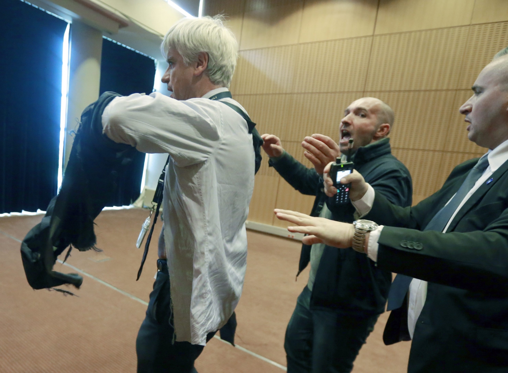 Air France assistant director long-haul flight, Pierre Plissonnier, left, is protected by security guards as he flees the Air France headquarters at Roissy Airport, north of Paris, France, after scuffles with union activists. Monday, Oct. 5, 2015. Union activists protesting proposed layoffs at Air France stormed the headquarters during a meeting about the job cuts, zeroing in on two managers who had their shirts torn from their bodies, scaled a fence and fled under police protection. (AP Photo/Jacques Brinon)