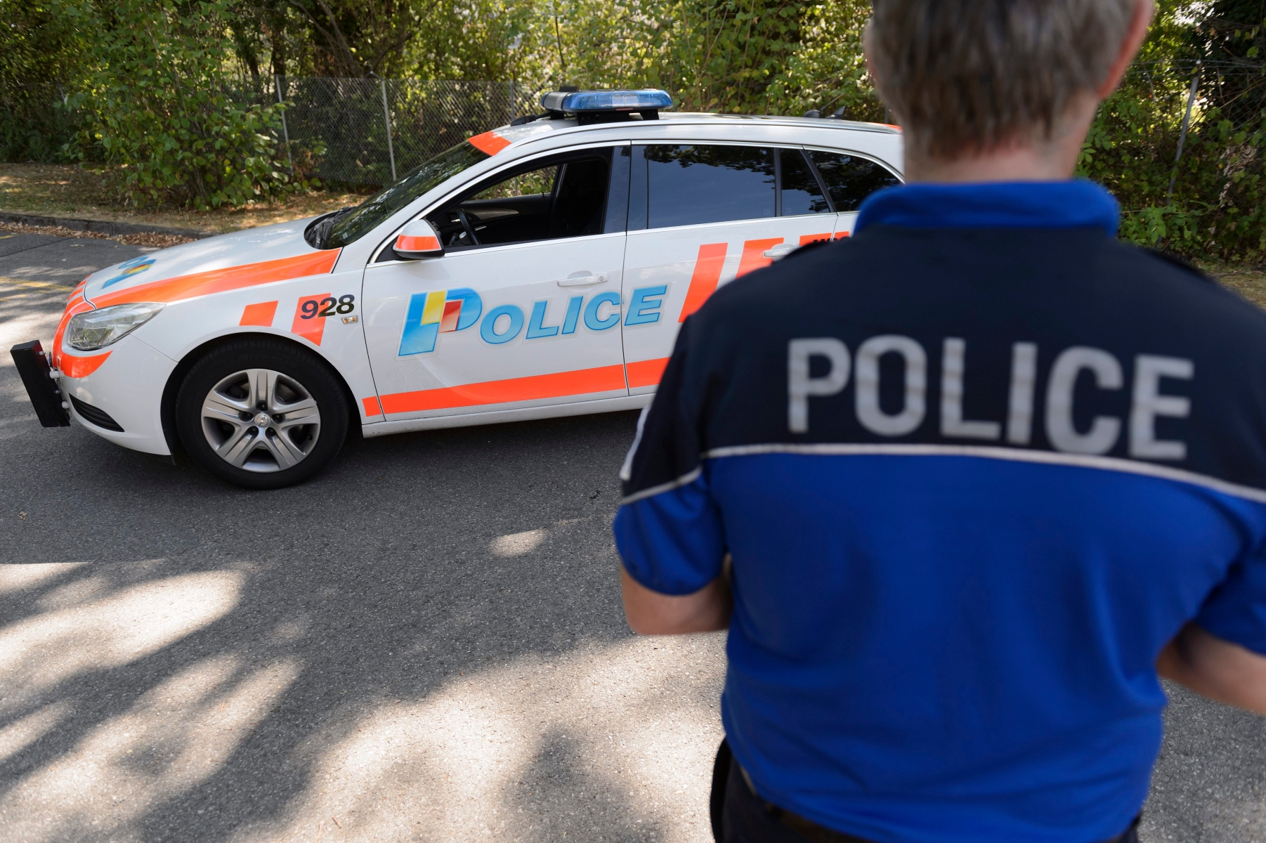 Un policier de la Police cantonale genevoise pose devant une voiture de police, pour des photos d'illustration, ce vendredi 31 juillet 2015 a Geneve. (KEYSTONE/Martial Trezzini) SCHWEIZ KANTONSPOLIZEI GENF