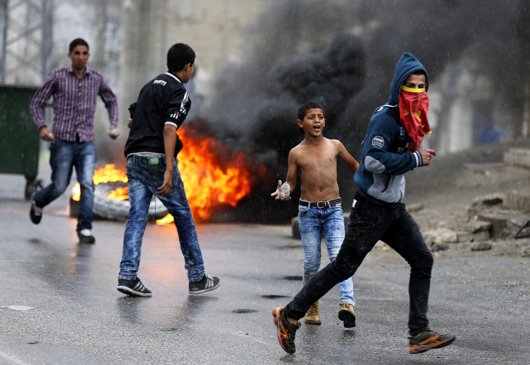 epa04994831 Palestinian protesters throw stones during clashes with Israeli soldiers in the West Bank village of Si'eer, north of Hebron , 25 October 2015. More than three weeks of unrest between Israelis and Palestinians has left more than 65 people dead. These include 57 Palestinians, eight Israelis and an Eritrean asylum seeker who was mistaken for an attacker and beaten to death by a mob in Israel.  EPA/ABED AL HASHLAMOUN MIDEAST PALESTINIANS ISRAEL