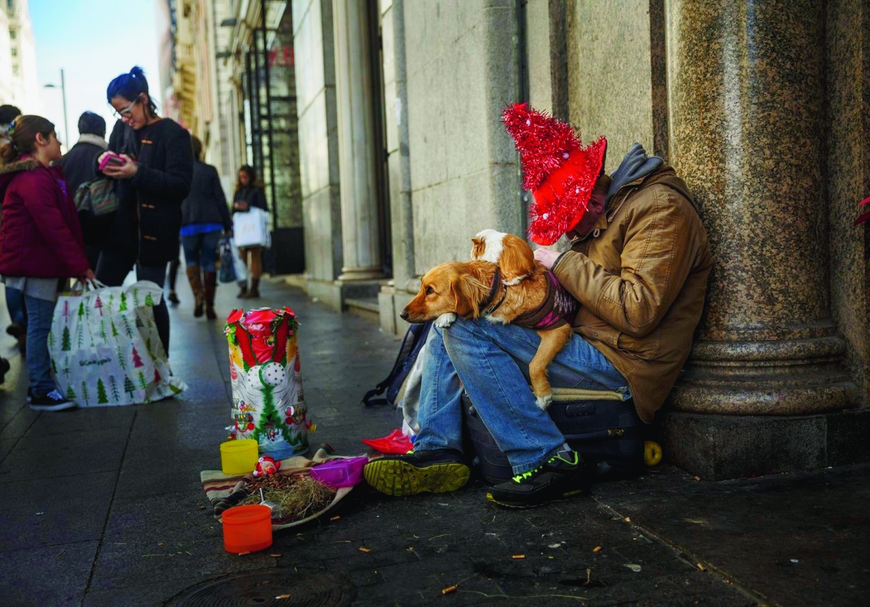 A man sleeps while begging with a dog and a Guinea pig on his knees in central Madrid, Wednesday, Dec. 9, 2015. (AP Photo/Daniel Ochoa de Olza) Spain Daily Life