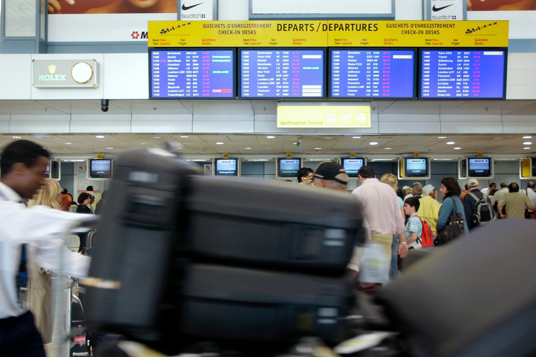 Un employe pousse des valises devant les guichets d'embarquement du terminal principal de l'Aeroport International de Geneve, ce mardi 27 mai 2008 a Geneve. L'Aeroport International de Geneve (AIG) a enregistre des resultats records en 2007. Son benefice net s'est etabli a 51 millions de francs, franchissant un nouveau cap. Le chiffre d'affaires progresse de 9,8% a 281,09 millions de francs. (KEYSTONE/Salvatore Di Nolfi) SUISSE BILAN AEROPORT GENEVE