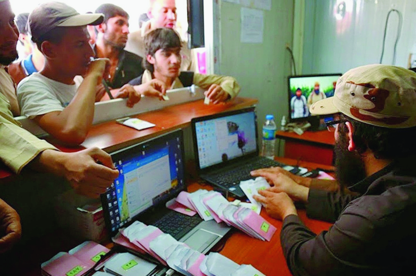 In this photo released on May 4, 2015 by a militant website, which has been verified and is consistent with other AP reporting, people stand at the window of a media distribution point to receive CDs from Islamic State militants, right, in Mosul, Iraq. (Militant website via AP) Inside The Caliphate Nation Of Fear